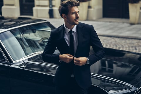 Elegant businessman in suit standing near luxury classic car