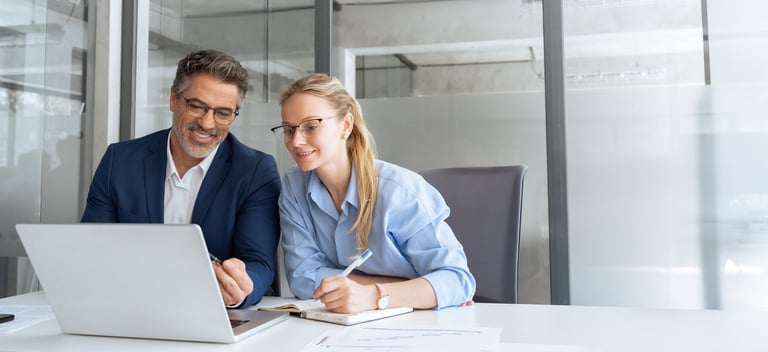 Mature mentor showing young employee project on laptop, passing down knowledge